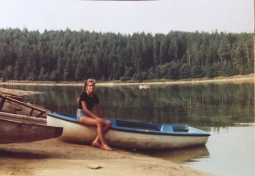 Auf dem Foto ist Claudia sitzend auf einem weiß-blauen Boot an einer Küste zu erkennen. Im Hintergrund ist noch ein Wald zu sehen.